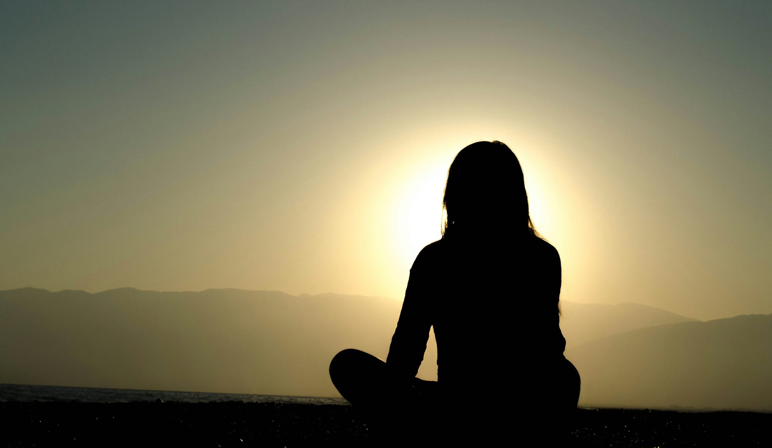 Mindful silhouette at sunset — photograph by Dingzeyu Li, Unsplash