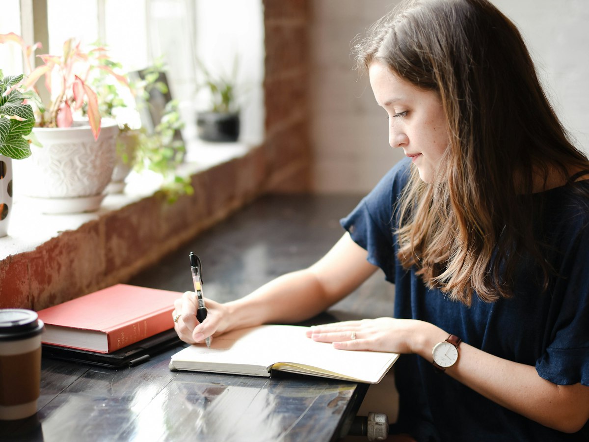 Person writing in a journal in a softly lit indoor setting